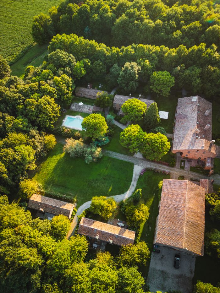 A stunning aerial view of an Italian countryside estate surrounded by lush greenery and a swimming pool.
